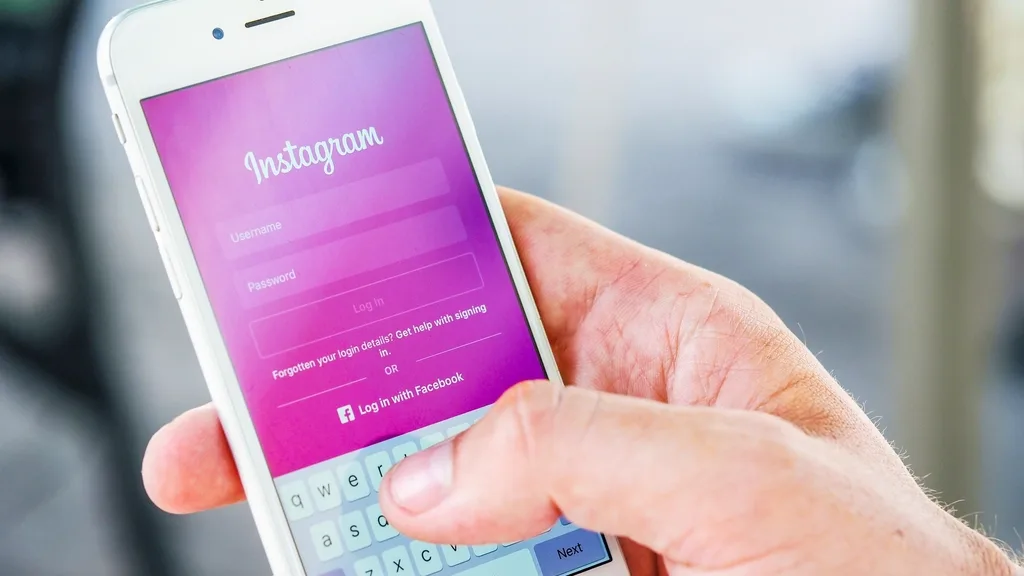 Mão segurando o celular com a tela de login do Instagram